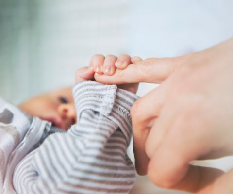 Baby umklammert mit dem Händchen einen Finger einer Hand