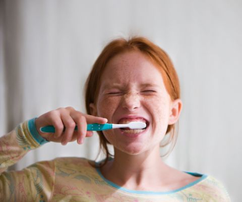 Rothaariges Mädchen putzt sich die Zähne