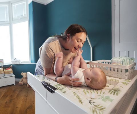 Una mamma cambia il pannolino al suo bebè sul fasciatoio