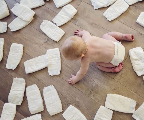 Ein Baby krabbelt zwischen vielen Windeln auf dem Boden