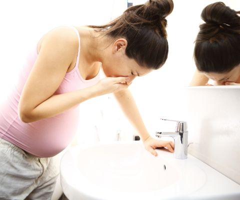 Schwangere beugt sich im Badezimmer über ein Waschbecken