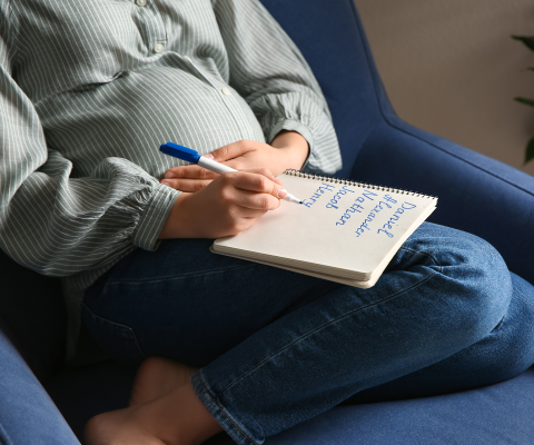 Schwangere mit Namenszettel auf dem Bauch