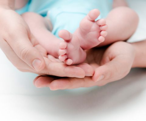 Kleine Babyfüsschen in den Händen der Mutter