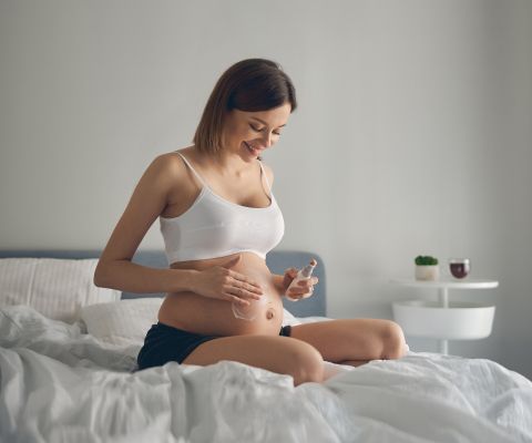 Una donna incinta si spalma la crema sulla pancia