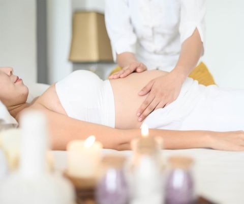 Une femme enceinte souriante se fait masser le ventre