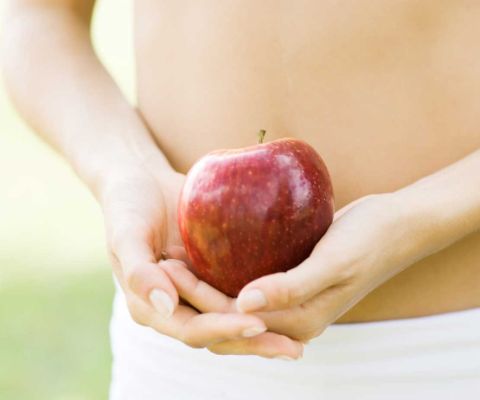 Frau mit Apfel vor dem Bauch