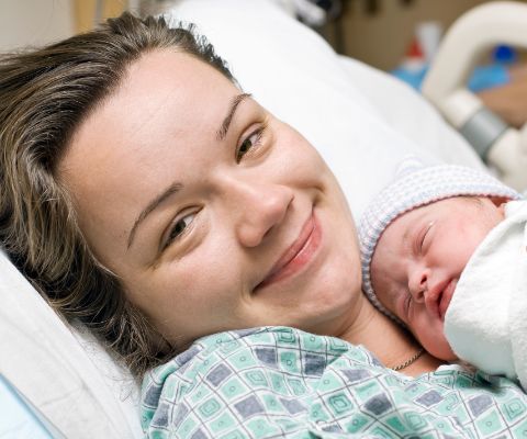 Glücklich lächelnde Mutter mit Baby im Arm