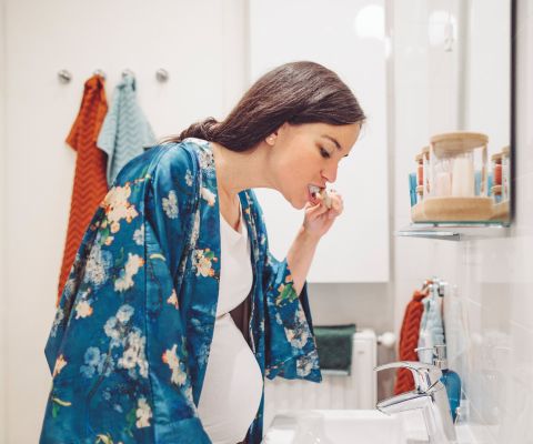 Donna incinta che si lava i denti in bagno
