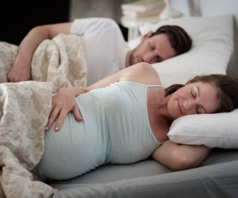 Donna incinta a letto sdraiata su un fianco
