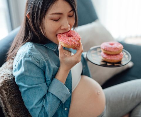 Donna incinta affamata che mangia un donut