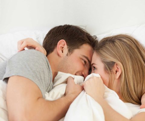 Un couple couché dans un lit se regarde mutuellement