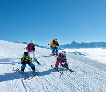 Familie fährt auf Skiern im Schuss den Hang hinunter