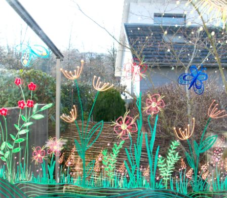 Ein mit Kreidemarker bemaltes Fenster mit frühlingshaften Motiven