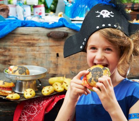 Bambino con cappello da pirata davanti a un buffet a tema pirata