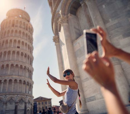 Une adolescente pose pour une photo devant un monument touristique. 