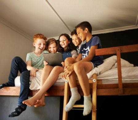 Kinder sitzen gemeinsam auf dem Hochbett