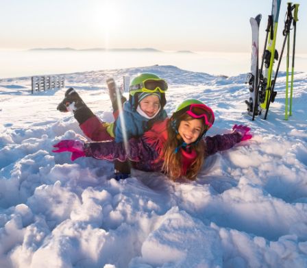 Zwei Kinder in Ski-Ausrüstung haben Spass im Schnee