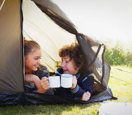 Enfants dans une tente une tasse à la main