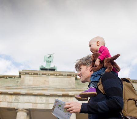 Padre con bambino piccolo sulle spalle davanti alla Porta di Brandenburgo