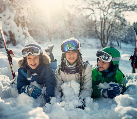 Trois enfants sont allongés côte à côte dans la neige