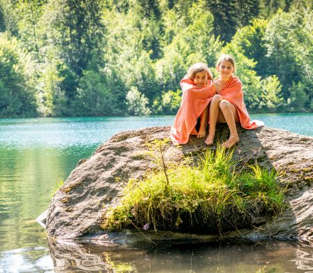 Zwei Kinder sitzen auf einer Badeinsel und wärmen sich im Handtuch