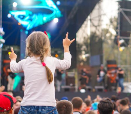 Ein kleines Mädchen auf einem Festival schaut auf die Bühne
