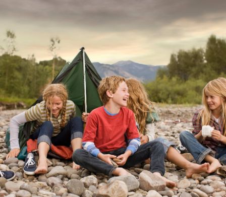 Kinder sitzen gemeinsam vor einem aufgeschlagenem Zelt