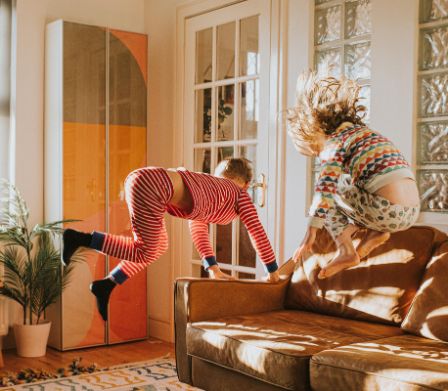 Zwei Kinder springen auf dem Wohnzimmer-Sofa