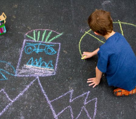 Junge malt mit Kreide auf Asphalt