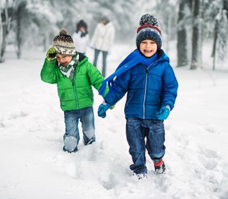Zwei kleine Jungen stapfen lachend durch den Schnee