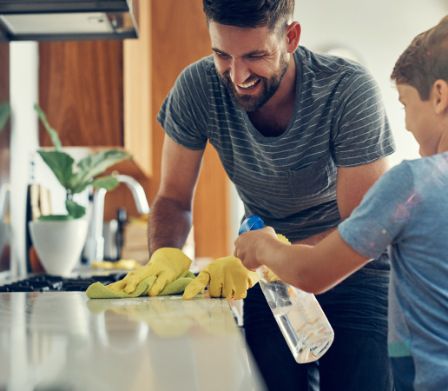 Un père et son garçon nettoyant le plan de travail de la cuisine