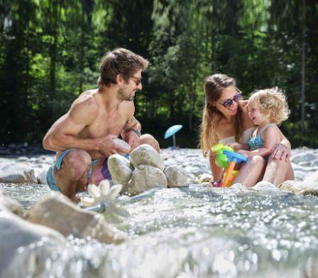 Des parents se baignent dans une rivière avec leur jeune enfant