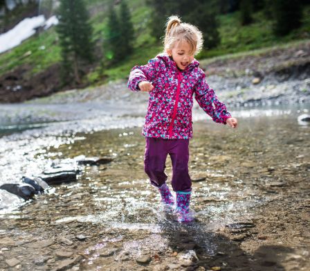 Enfant courant dans un ruisseau avec des bottes en caoutchouc