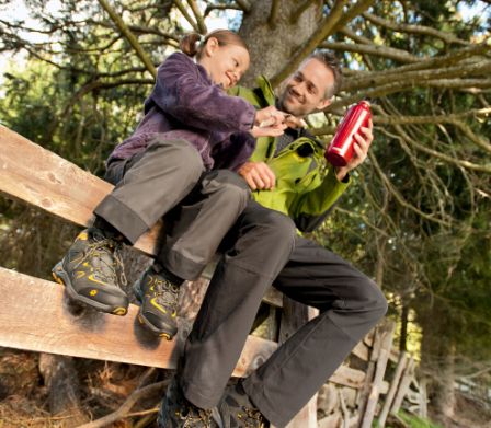 Kind und Vater mit Wanderschuhen sitzen auf einer Bank