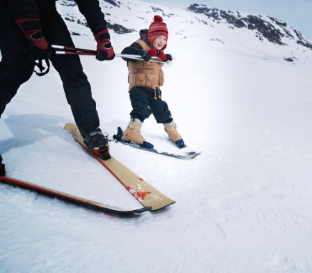 Jeune enfant apprenant à skier et se tenant fermement à ses bâtons