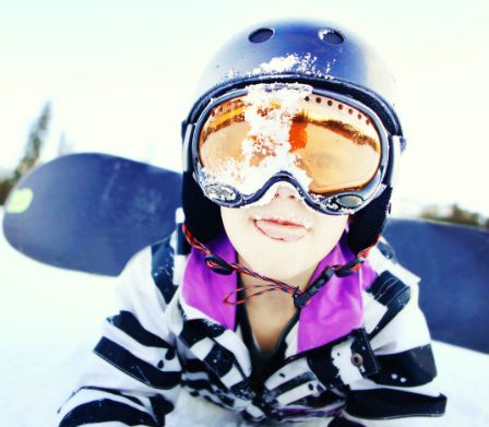 Ragazzo con occhiali da sci nei suoi primi tentativi con lo snowboard