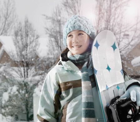 Fille en vêtements de sports d’hiver avec un snowboard