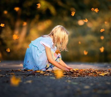 Fillette jouant avec les feuilles d’automne.