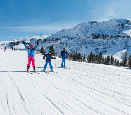Familie fährt Ski auf einer breiten Skipiste