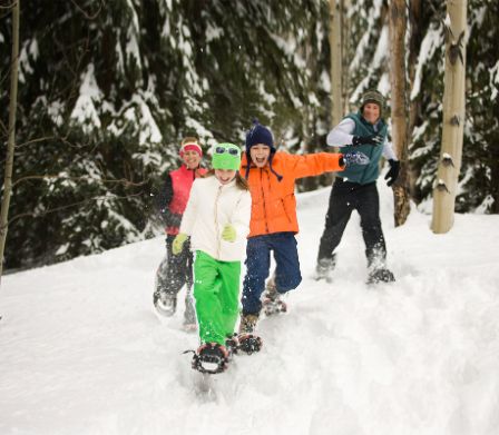 Familie mit grösseren Kindern haben Spass beim beim Schneeschuhlaufen