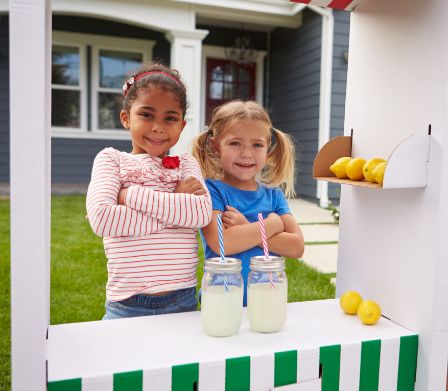 Deux fillettes vendent de la limonade faite maison.