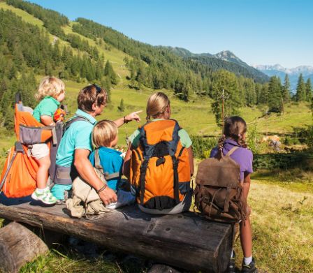 Una famiglia con attrezzatura da escursionismo siede su una panchina di fronte a una bellissima vista