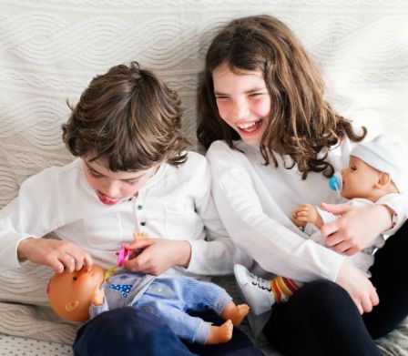 Mädchen und Junge spielen mit Puppen