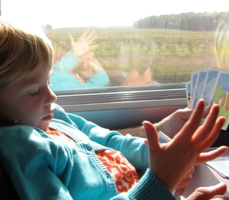 Kind im Zug mit Spielkarten in der Hand