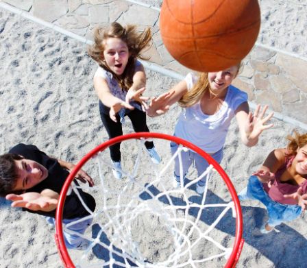 Kinder spielen Basketball und werfen den Ball auf den Korb