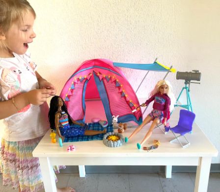 Petite fille ravie à la vue du set de tente de camping Barbie