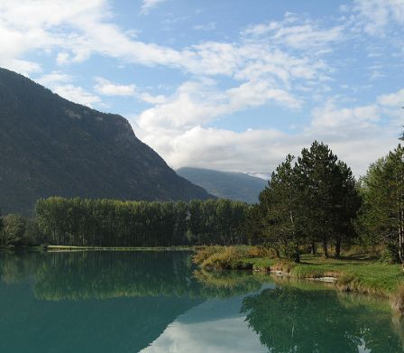 Riva di un lago con vista su alberi e montagne