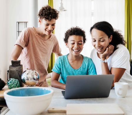 Mutter mit Söhnen gestalten digitale Einladungen am Laptop