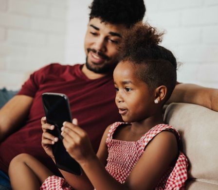 Père et fille penchés sur un smartphone