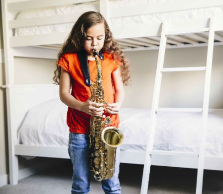 Una bambina si esercita a casa con il suo strumento musicale